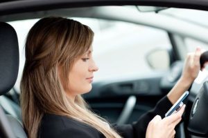 pretty woman texting in a reckless manner behind wheel 