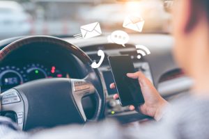 man holding phone while driving | Cell Phone Use and Car Accident Risk