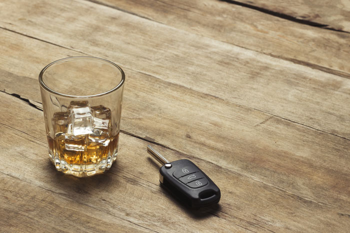 whiskey glass and car key on wooden table