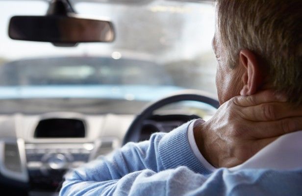 man in blue whiplash behind wheel | Causes of Your Neck and Back Pain