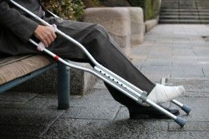 man with crutches sitting on a park bench | Premises Liability Injury Claims