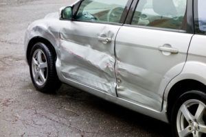 white sedan with dented door after accident | Black Forest Car Accident Lawyers